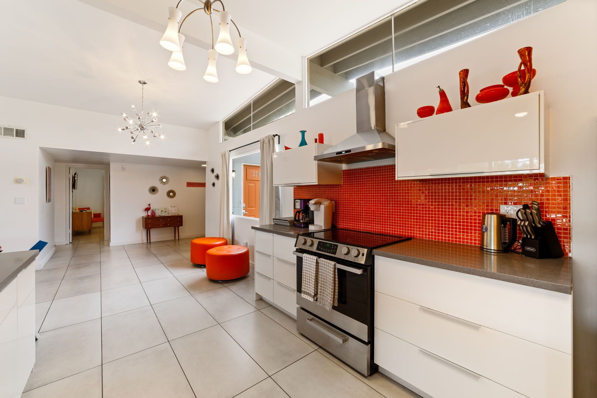 A modern kitchen with a red backsplash, stainless steel appliances, and a bright pendant light.