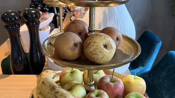 Un puesto de frutas de tres niveles con manzanas y plátanos sobre una mesa de madera en un bar.