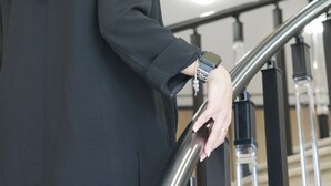 Una persona baja por una escalera moderna con barandillas de metal y detalles de madera.