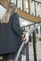 Una persona baja por una escalera moderna con barandillas de metal y detalles de madera.