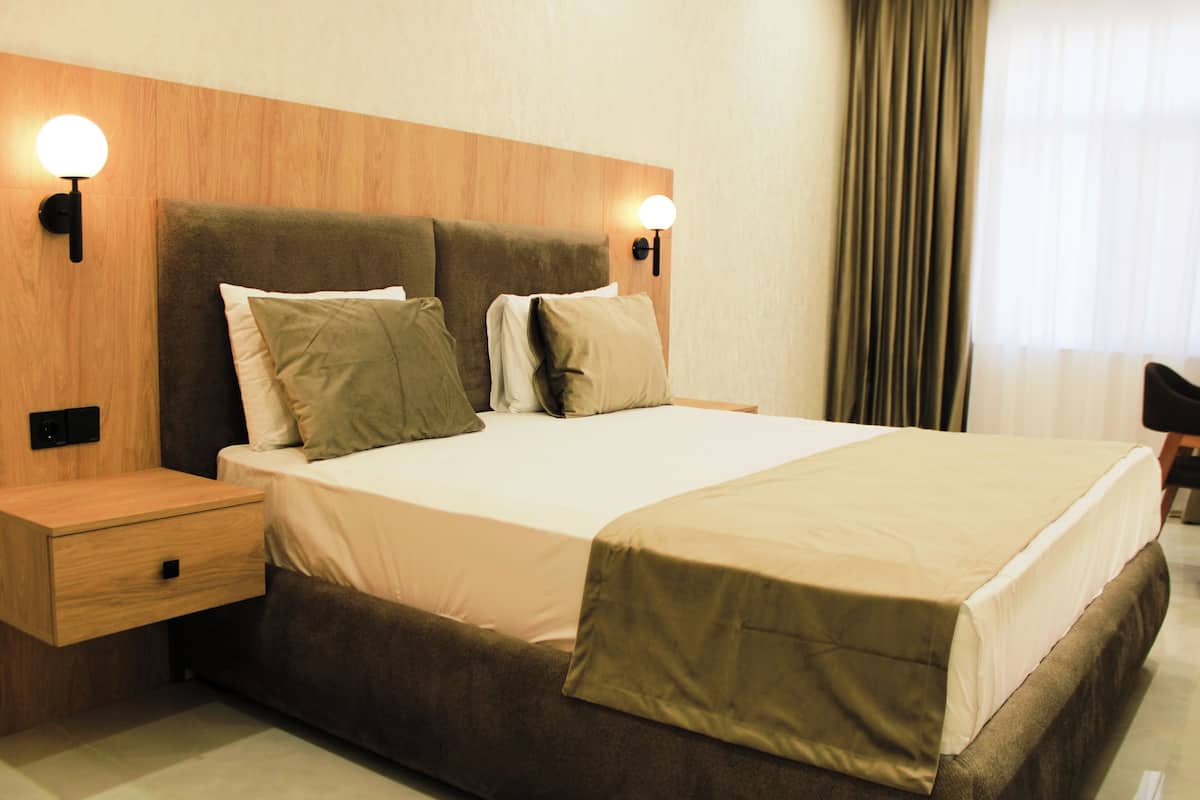 A hotel room with a large bed, two bedside tables, and wall-mounted lighting.