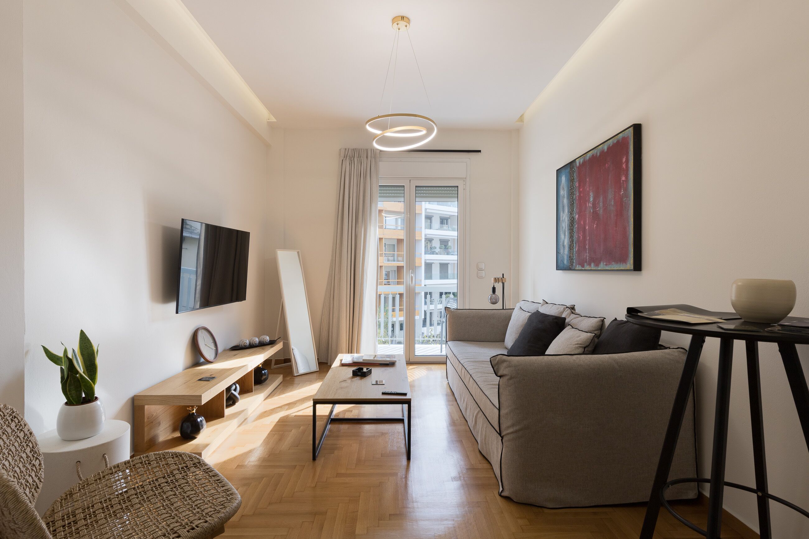 Una sala moderna con un sofá, una mesa de centro y un televisor montado en la pared.
