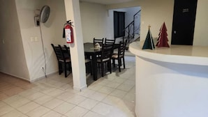 A dining area with a table and chairs, a fire extinguisher, a small Christmas tree, and a staircase. - Casa Seloria (Cancún)