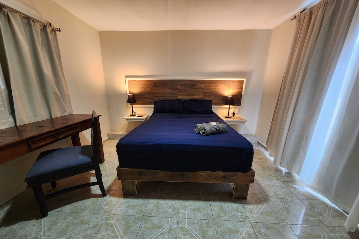 A hotel room with a bed, a desk, and a chair.