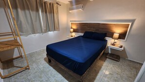 A bedroom with a bed, wooden headboard, bedside tables with lamps, a wardrobe, and a window with curtains. - Casa Seloria (Cancún)