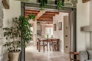 Ein Essbereich mit Holztisch und -stühlen, einem Blumentopf und einer Steinwand.