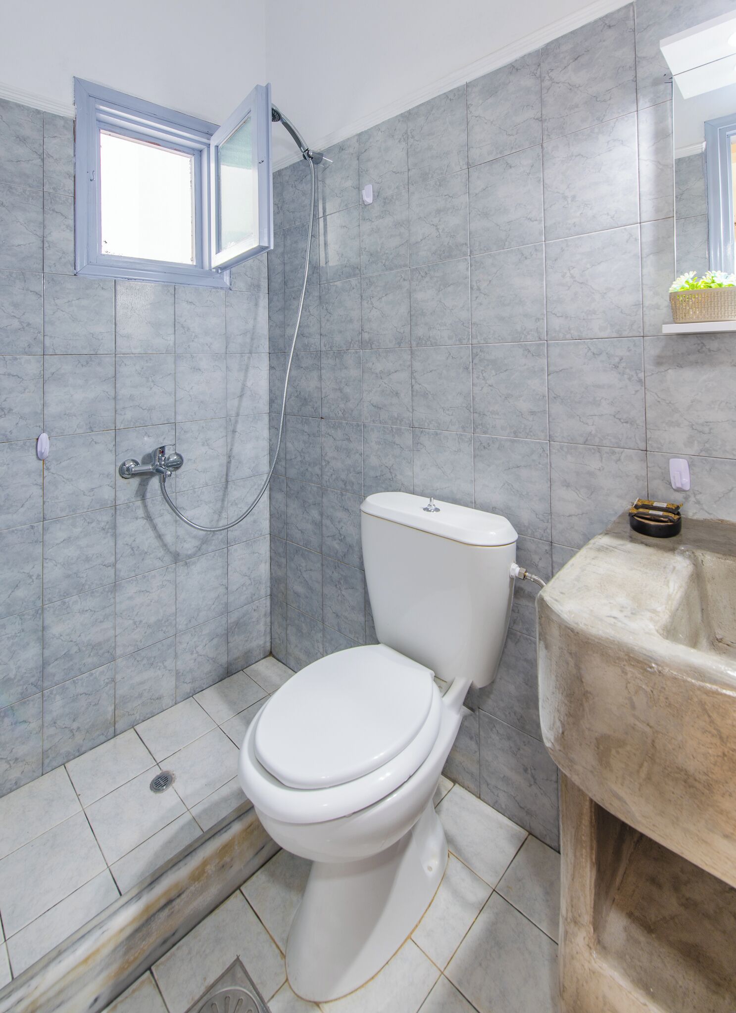 A bathroom with a toilet, shower, and sink.