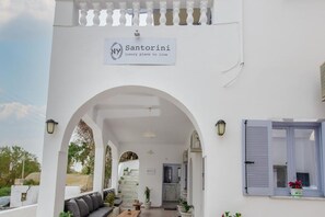 Un edificio blanco con una entrada arqueada, un letrero que dice 'Santorini luxury place to live' y una escalera que conduce al interior.