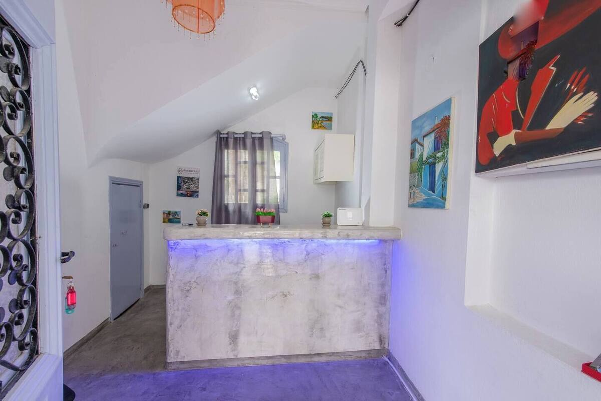 A reception area with a marble counter, a door with a metal gate, a window with curtains, and a painting on the wall.