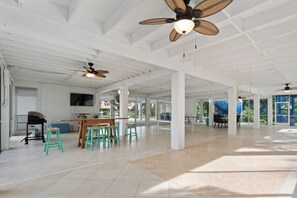 A spacious indoor area with high ceilings, multiple ceiling fans, and a large table with chairs. - ☀️Canal Front | Preserve Access | Tons of Family Fun | Flamingo Bayou B☀️ (Fort Myers Beach)