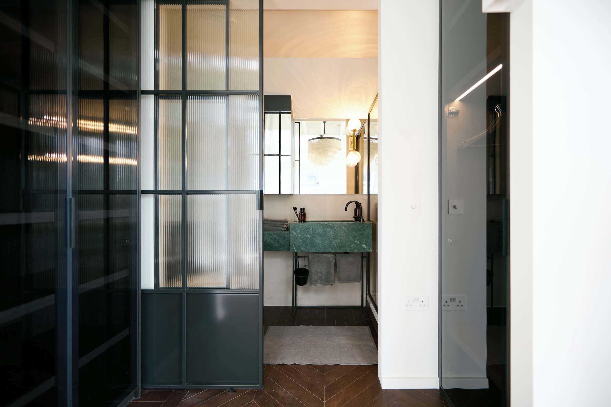 A modern kitchen with a green countertop, a sink, and a hanging towel rack.