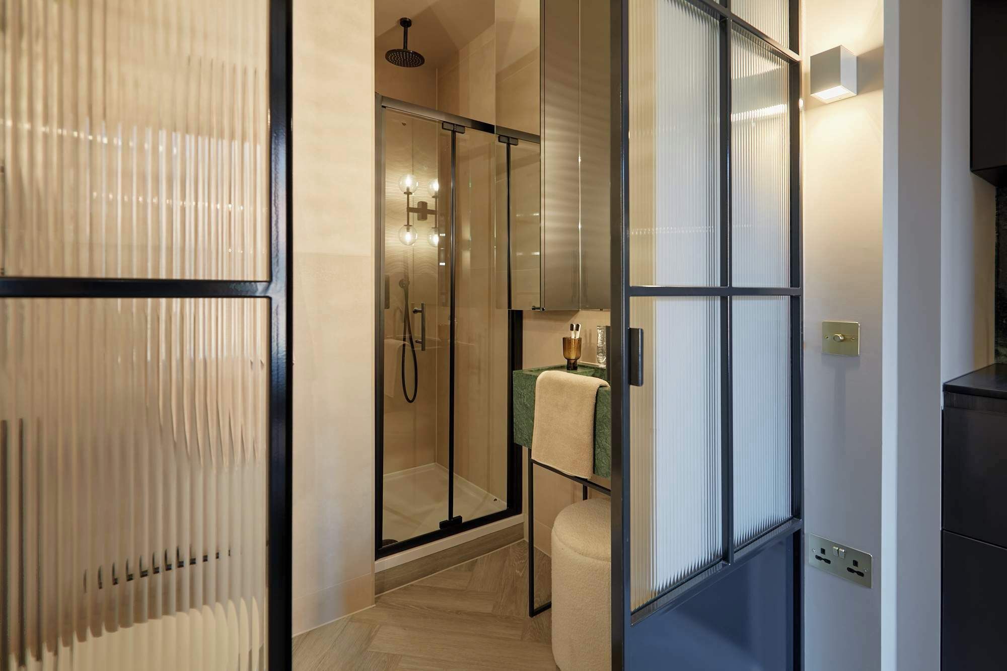 Un baño moderno con cabina de ducha de vidrio, un perchero y encimera verde.