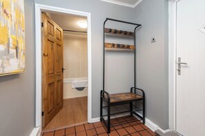 A hallway with a wooden door, a metal rack with hooks, and a tiled floor. - Toast Stays · River-Twine (Croxdale)