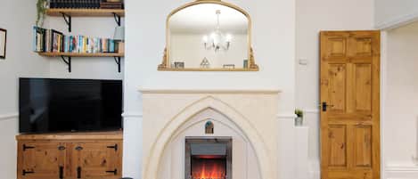 A living room with a fireplace, a television, and bookshelves.