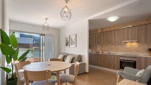 Une cuisine moderne avec des meubles en bois, un coin repas doté d’une table ronde et de chaises, et une vue sur l’extérieur grâce à de grandes fenêtres.