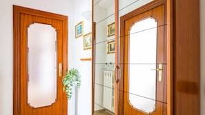 Une porte en bois avec un panneau en verre dépoli, un radiateur blanc et une plante en pot.