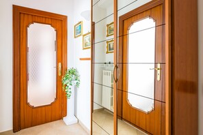 A wooden door with a frosted glass panel, a white radiator, and a potted plant. - Casa MariaPia al Vomero by Napoliapartments (Naples)