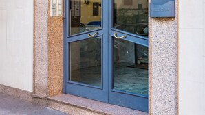 Une entrée d’immeuble avec une porte en verre, un panneau indiquant le numéro de l’immeble et une plaque.