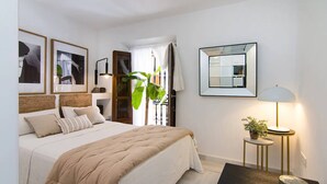 Una camera da letto con un letto, comodini, uno specchio e quadri appesi al muro.