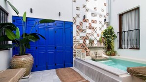 A pool area with a blue door, a tiled wall, and a small fountain. - Riad Alhambra 1 (granada)
