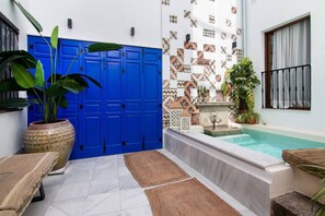 A pool area with a blue door, a tiled wall, and a small fountain. - Riad Alhambra 1 (granada)