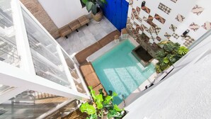 Una piscina sul tetto con una caratteristica d'acqua cristallina, circondata da piante in vaso e un muro decorato.