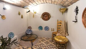 Ein Zimmer mit Fliesenboden, einem Holzstuhl, einem Glastisch und verschiedenen dekorativen Tellern an den Wänden.