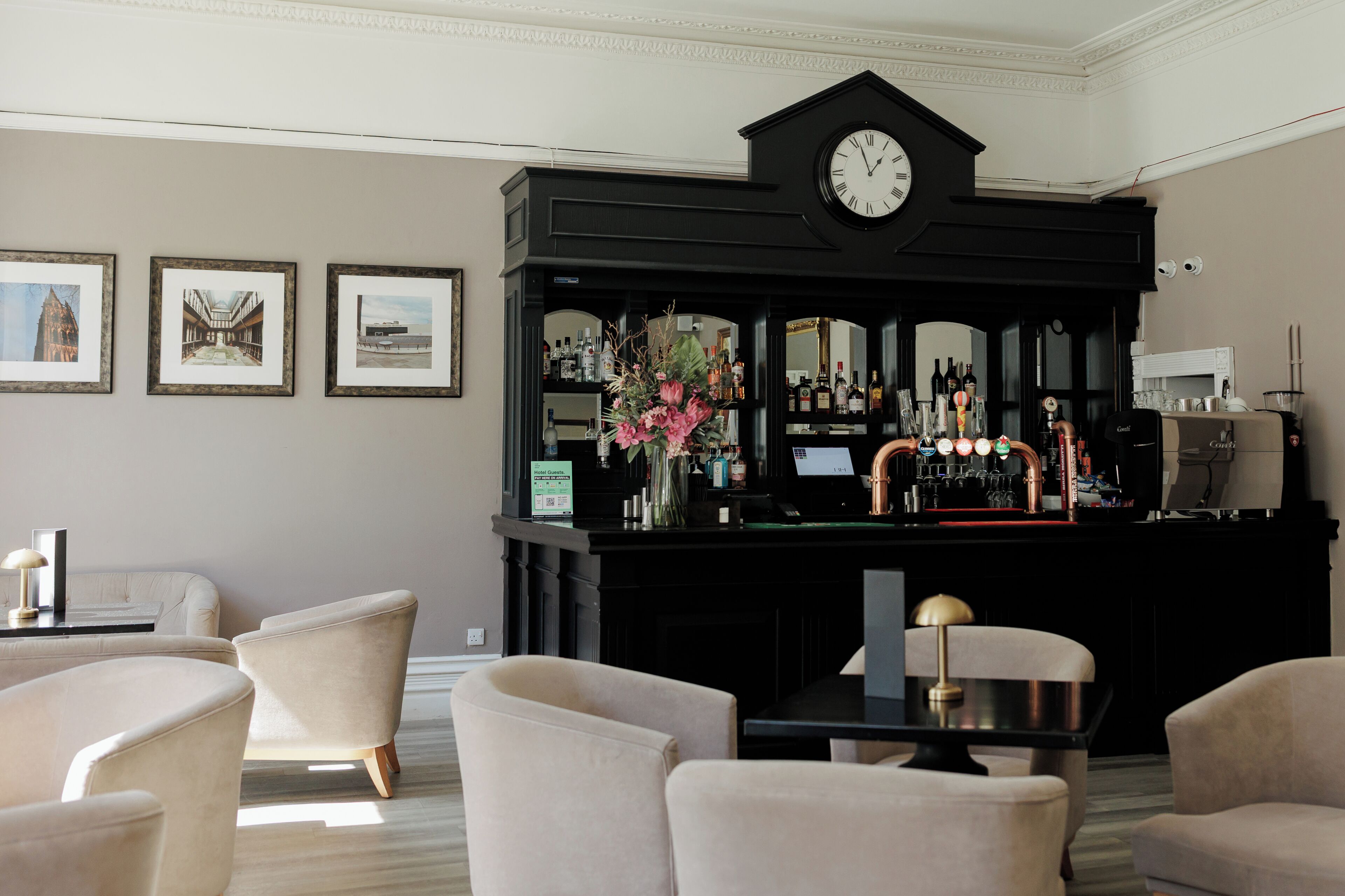 Eine Bar mit einer Uhr, Barhocker und gerahmten Bildern an der Wand.