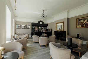 A spacious living room with a fireplace, a bar area, and a large mirror. - Brandon Hall Hotel and Spa (Coventry)