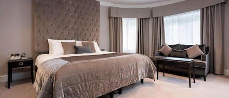 Une chambre à coucher avec un grand lit, une tête de lit capitonnée, un canapé et une table de chevet.