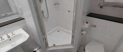 Un baño con ducha, inodoro, lavamanos y suelo con estampado de cuadros.
