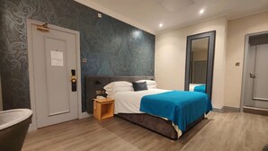 A hotel room with a bed, a nightstand, a mirror, and a door. - Brandon Hall Hotel and Spa (Coventry)
