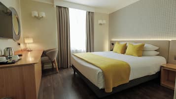 Hotelkamer met een bed, nachtkastjes, een bureau, een stoel, een spiegel en een raam met gordijnen.