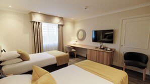A hotel room with two beds, a desk, a chair, a television, and a window with curtains. - Brandon Hall Hotel and Spa (Coventry)