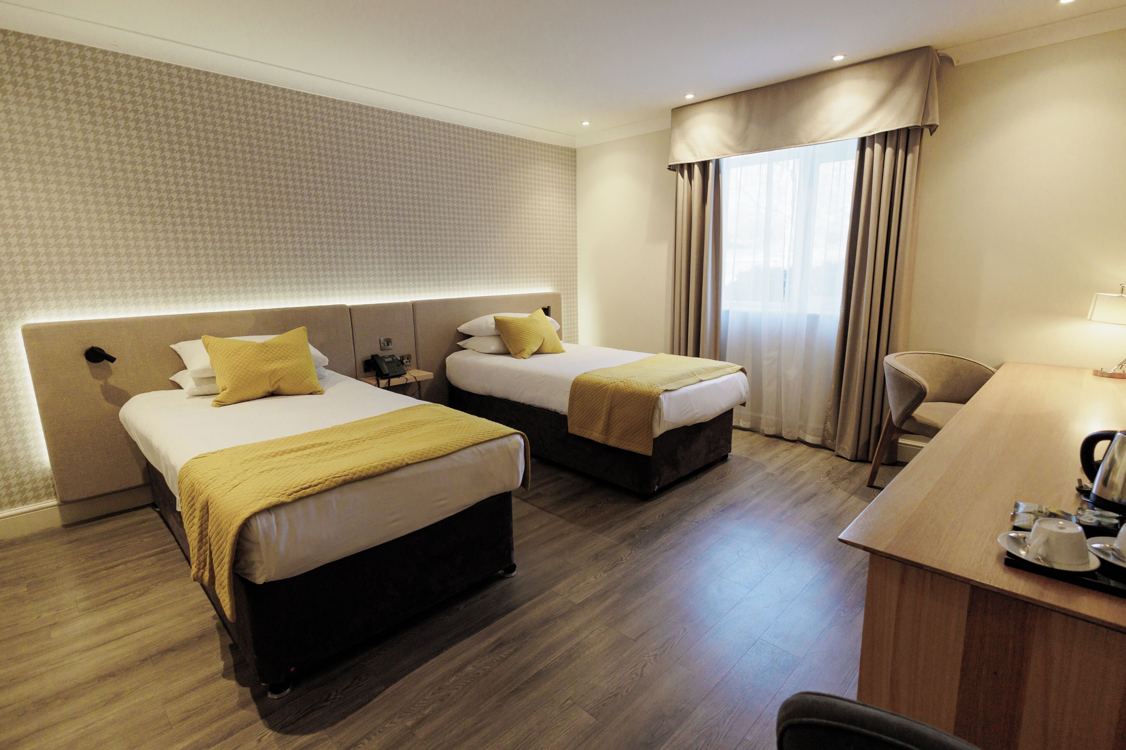 A hotel room with two beds, a desk, and a chair.