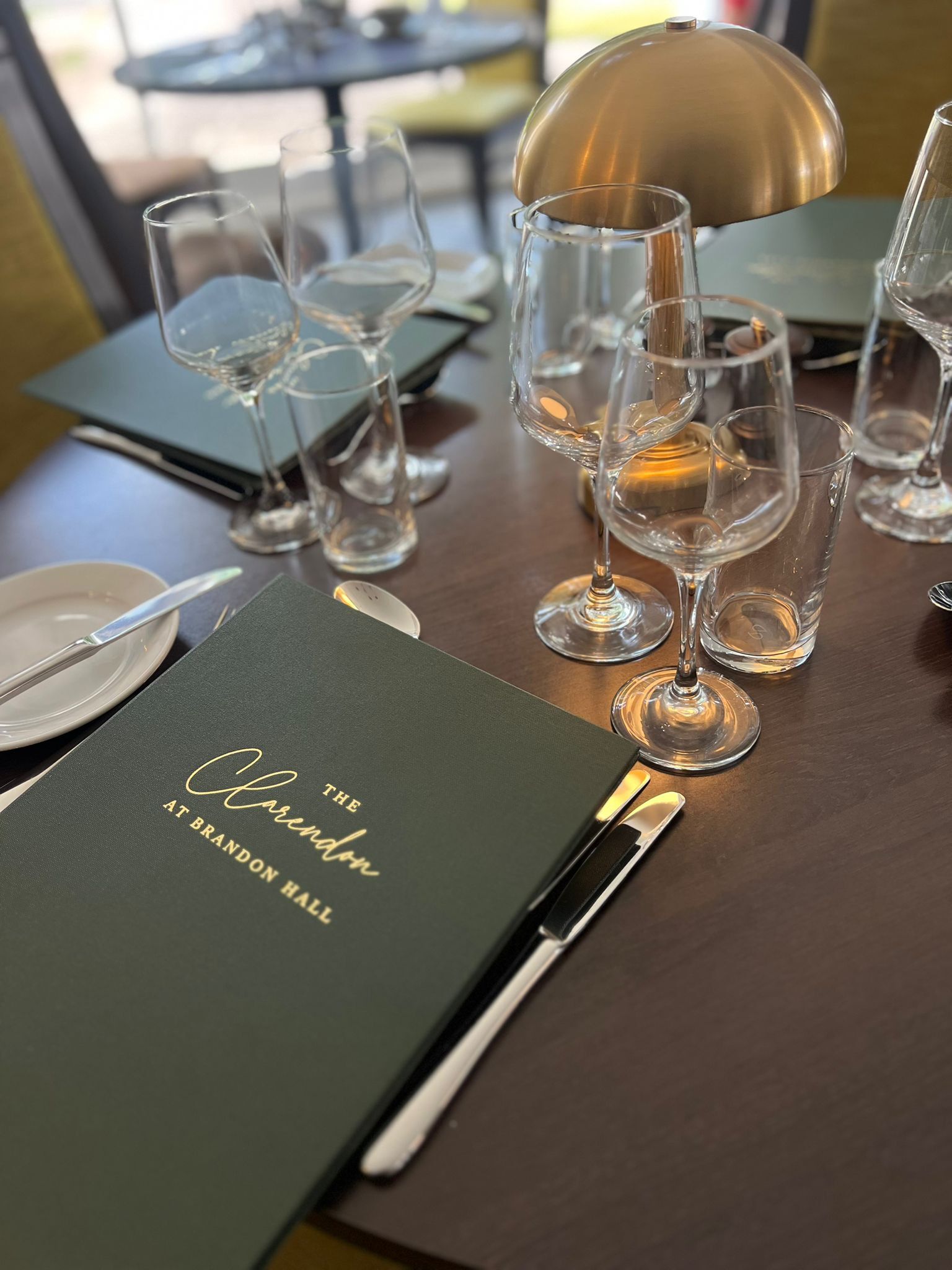 A table set with wine glasses, a menu, and cutlery.