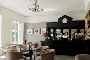 A bar area with a clock, framed pictures on the wall, and a bar counter with bottles. - Brandon Hall Hotel and Spa (Coventry)