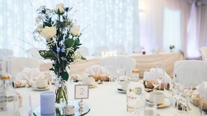 A wedding reception table set with white tablecloths, numbered place settings, and a centerpiece of white flowers. - Brandon Hall Hotel and Spa (Coventry)
