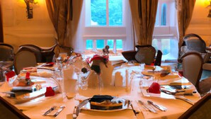 A dining table set for a meal with chairs around it, a chandelier above, and curtains on the windows. - Brandon Hall Hotel and Spa (Coventry)