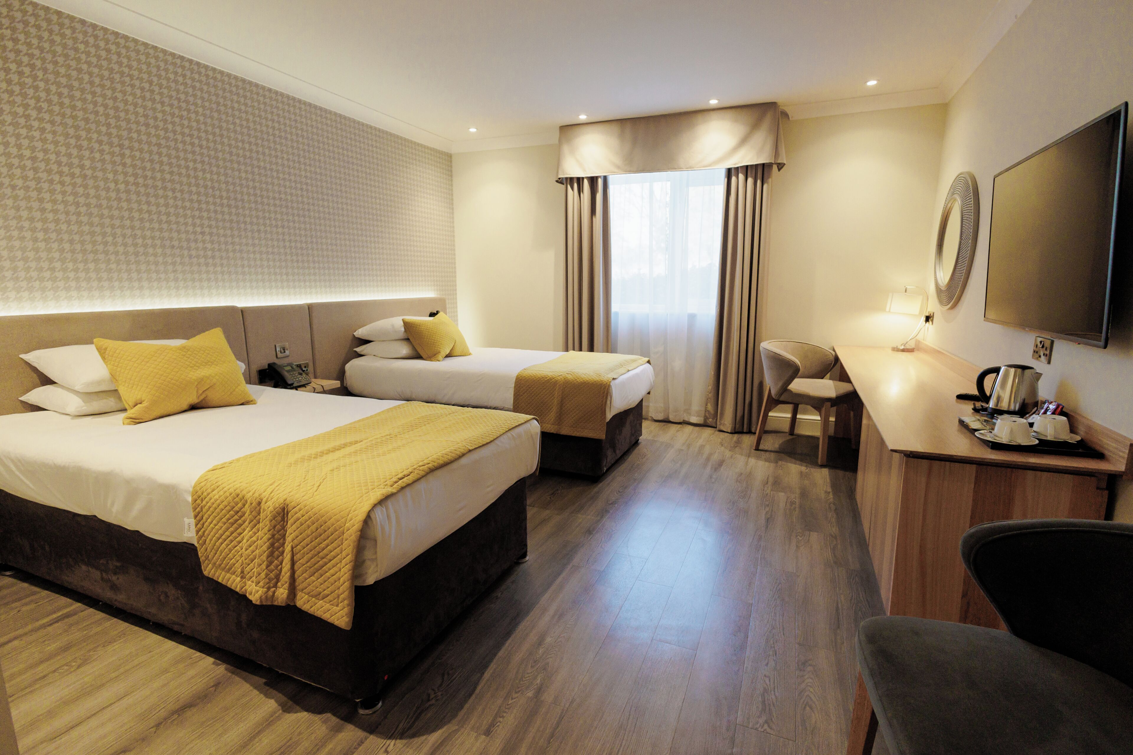 A hotel room with two beds, a desk, a chair, and a television.