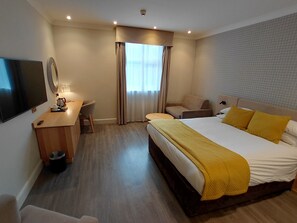 A hotel room with a bed, a desk, a chair, a television, and a window with curtains. - Brandon Hall Hotel and Spa (Coventry)