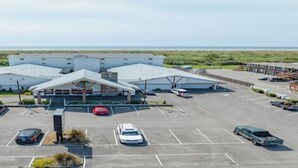 A large, modern building with a central atrium and multiple parking spaces. - 1 King Bed Non-Smoking (Ocean Shores)