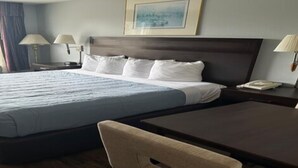 A hotel room with a large bed, bedside lamps, a desk, and a window with curtains. - 1 King Bed Non-Smoking (Ocean Shores)