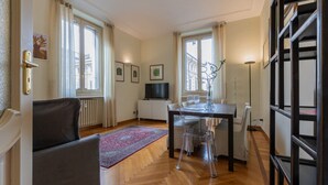 Ein modernes Wohnzimmer mit einer Couch, einem Esstisch mit Stühlen, einem Fernseher und einem Kamin.