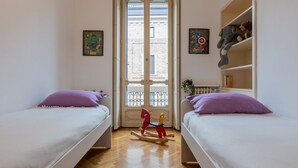 Ein Zimmer mit zwei Betten, einem hölzernen Schaukelpferd und einem Bücherregal mit Stofftieren.