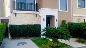 A two-story residential building with a balcony, large windows, and a well-maintained garden. - Stylish Home via Samborondon - No Pets Allowed (Guayaquil)