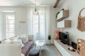 Ein modernes Wohnzimmer mit Sofa, Couchtisch, Fernseher und Dekorationselementen.