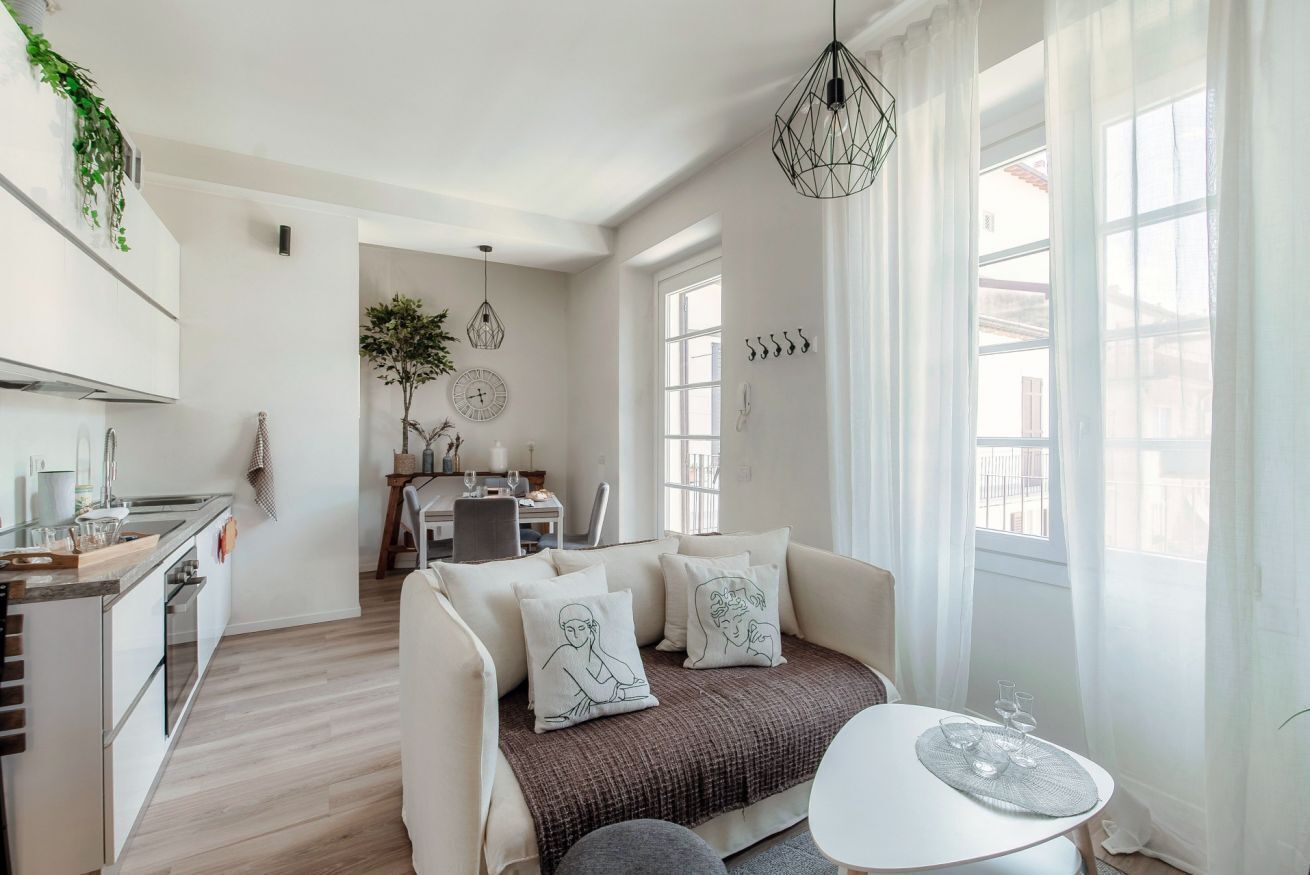 A modern living room with a sofa, a dining area, and a kitchen.