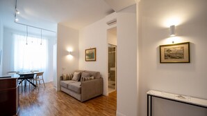 Un soggiorno moderno con pavimento in legno, un divano, un tavolo da pranzo con sedie e un quadro appeso al muro.