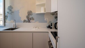 Una cucina moderna con piano cottura integrato, lavello e finestra vista alberi e palazzi.